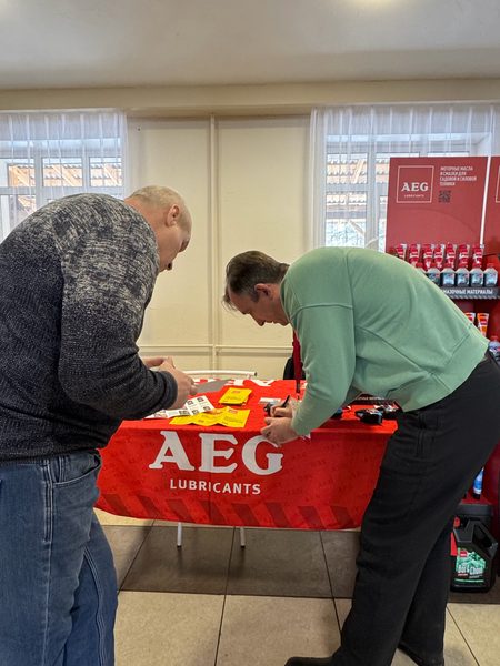 Участники конференции у стола AEG Lubricants с каталогами и листовками
